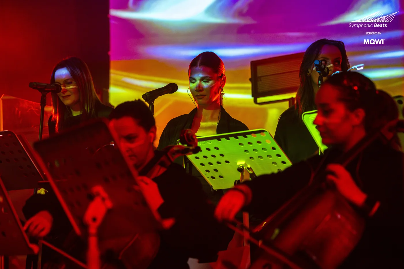 Wokalistki i sekcja smyczkowa w kolorowym świetle sceny